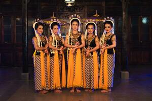 een groep van Javaans dansers staand met hun vrienden terwijl vervelend geel kostuums en sjaals foto