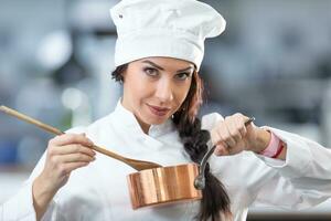 mooi vrouw chef houdt een koper pan en houten lepel, oor een profesional algemeen foto