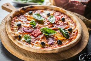 pizza diavolo traditioneel Italiaans maaltijd van pittig salami peperoni Chili ui olijven en basilicum foto