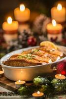Kerstmis avondeten van vis Zalm in roosteren schotel met feestelijk decoratie komst krans en kaarsen. foto