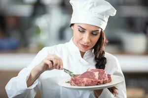 professioneel gekleed chef borstels rauw steak Aan een bord met voorjaar van vers rozemarijn foto