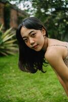 portret van een Indonesisch vrouw met gekruld armen en zwart haar- vervelend een sexy gedrukt jurk foto