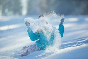 gelukkig jong pre-tiener meisje in warm kleding spelen met sneeuw foto