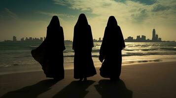 drie Dames in traditioneel kleding staand Bij Dubai s strand. silhouet concept foto