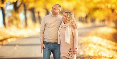 een volwassen paar in liefde Aan een wandelen in de herfst gouden steeg foto