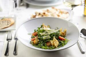 tafel reeks voor een lunch of avondeten met raket salade met tomaten, physalis en Parmezaanse kaas foto