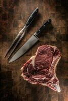 rib oog steak met bot Aan slager bord met vork en mes foto