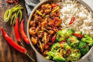 top visie van een Aziatisch stijl teriyaki kip met rijst, broccoli en chili Aan een wijnoogst tafel foto