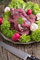 rauw rundvlees vlees met vers groente. gesneden rundvlees steak in sla salades radijs en champignons. foto