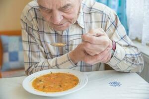 ouderen Mens met parkinsons ziekte houdt lepel in beide handen foto