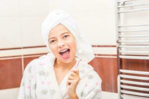 tiener- meisje in badkamer met tandenborstel. ochtend- en avond tandheelkundig hygiëne foto