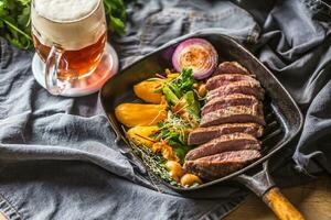 rundvlees flank steak in rooster pan met zute aardappel puree knoflook kruid decoratie en droogte bier foto