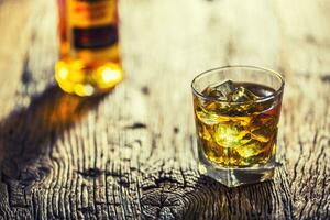 whisky. whisky drinken met ijs kubussen Aan oud rustiek eik tafel foto