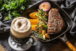 rundvlees flank steak in rooster pan met zute aardappel puree knoflook kruid decoratie en droogte bier foto