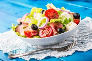 salade. vers zomer sla salade.gezond middellandse Zee salade olijven tomaten Parmezaanse kaas kaas en prosciutto foto