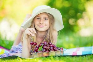 kind met kersen. weinig meisje met vers kersen. portret van een glimlachen jong meisje met kom vol van vers kersen. foto