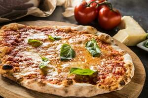 Italiaans traditioneel pizza margarita Aan ronde houten bord met basilicum tomaten en Parmezaanse kaas foto