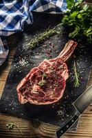 rauw rundvlees tomahawk steak met zout peper en rozemarijn Aan leisteen bord foto