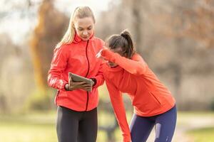 een jong vrouw trainer en een junior zijn controle haar sport- prestatie Aan een tablet foto
