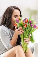 donker haren vrouw ruiken lief aroma van vers kleurrijk tulpen foto