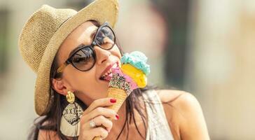 mooi gelukkig vrouw likt ijs room gedurende een heet zomer dag foto