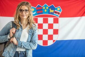 Kroatisch leerling in bril staat in voorkant van vlag van Kroatië foto