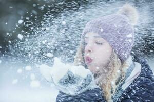 mooi jong vrouw in warm kleding blazen sneeuw foto