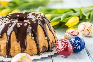 heerlijk vakantie Slowaaks en Tsjechisch taart babovka met chocola glazuur. Pasen decoraties - voorjaar tulpen en eieren foto