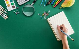 leerling van de meisje hand- van een potlood met notitieboekje en school- benodigdheden foto