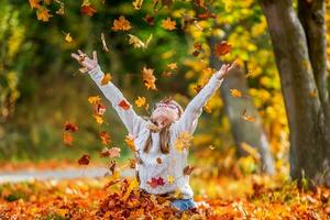 kind gelukkig het werpen oranje bladeren bovenstaand haar gedurende herfst foto