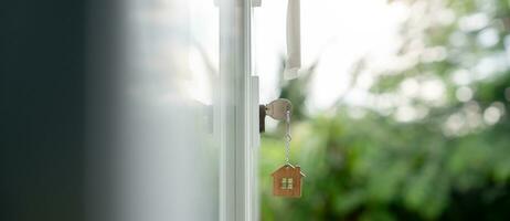 landheer sleutel voor ontgrendelen huis is aangesloten in de deur. tweede hand- huis voor huur en uitverkoop. sleutelhanger is blazen in de wind. hypotheek voor nieuw huis, kopen, verkopen, renoveren, investering, baasje, landgoed foto