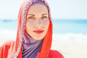 een vrouw vervelend een rood hoofddoek Aan de strand foto