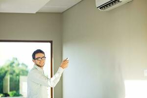een Mens is staand in voorkant van een muur gemonteerd lucht conditioner foto