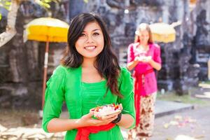 een vrouw in een groen jurk Holding een kom van voedsel foto