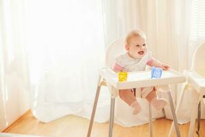 een baby zittend in een hoog stoel met een speelgoed- foto