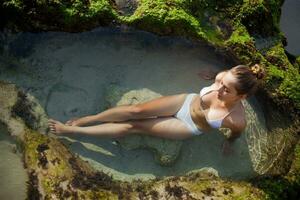 een vrouw in een bikini aan het liegen in de water foto