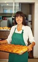 een vrouw Holding een dienblad van gebakken goederen foto