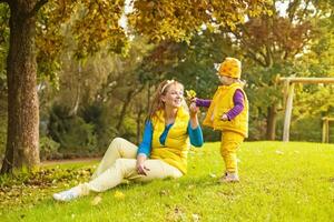 een vrouw en kind in geel kleding zittend Aan de gras foto