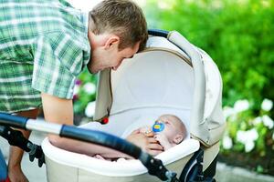 een Mens is Holding een baby in een wandelwagen foto