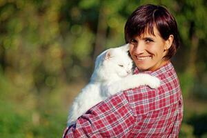 een vrouw in een plaid overhemd Holding een wit kat foto