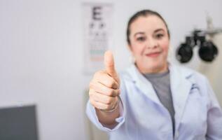 vrouw optometrist met duim omhoog in de laboratorium. optometrie specialist met duim omhoog. glimlachen oog dokter met duim omhoog in kantoor foto