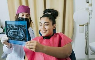 geduldig op zoek Bij röntgenstraal met tandarts, concept van tandarts tonen röntgenstraal examen naar vrouw geduldig, tandarts tonen geduldig röntgenfoto. tandarts met geduldig herzien de röntgenstraal foto