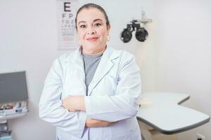 portret van vrouw optometrist met armen gekruiste in de laboratorium. glimlachen vrouw oogarts met armen gekruiste in kantoor foto