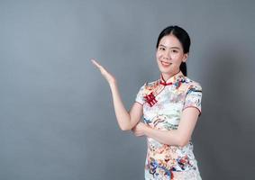 mooie jonge aziatische vrouw draagt chinese traditionele kleding met hand presenteren aan de zijkant foto