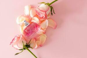 een chique fles van parfum of eau de parfum met aantekeningen van delicaat rozen Aan een roze achtergrond met roos bloemblaadjes, rozenknopjes. top visie. een kopiëren ruimte. foto