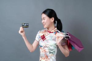 aziatische vrouw draagt chinese traditionele kleding met boodschappentas en creditcard foto