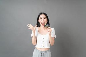 Aziatische vrouw met blij gezicht en creditcard in de hand die vertrouwen en vertrouwen toont voor het doen van betaling foto
