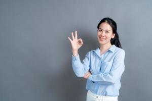 jonge aziatische vrouw die lacht en een goed teken toont foto