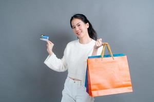 mooie aziatische vrouw met boodschappentassen en creditcard tonen