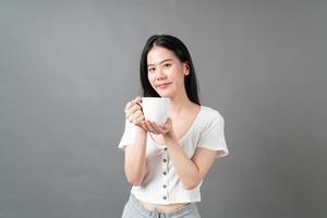 jonge Aziatische vrouw met blij gezicht en hand met koffiekopje foto